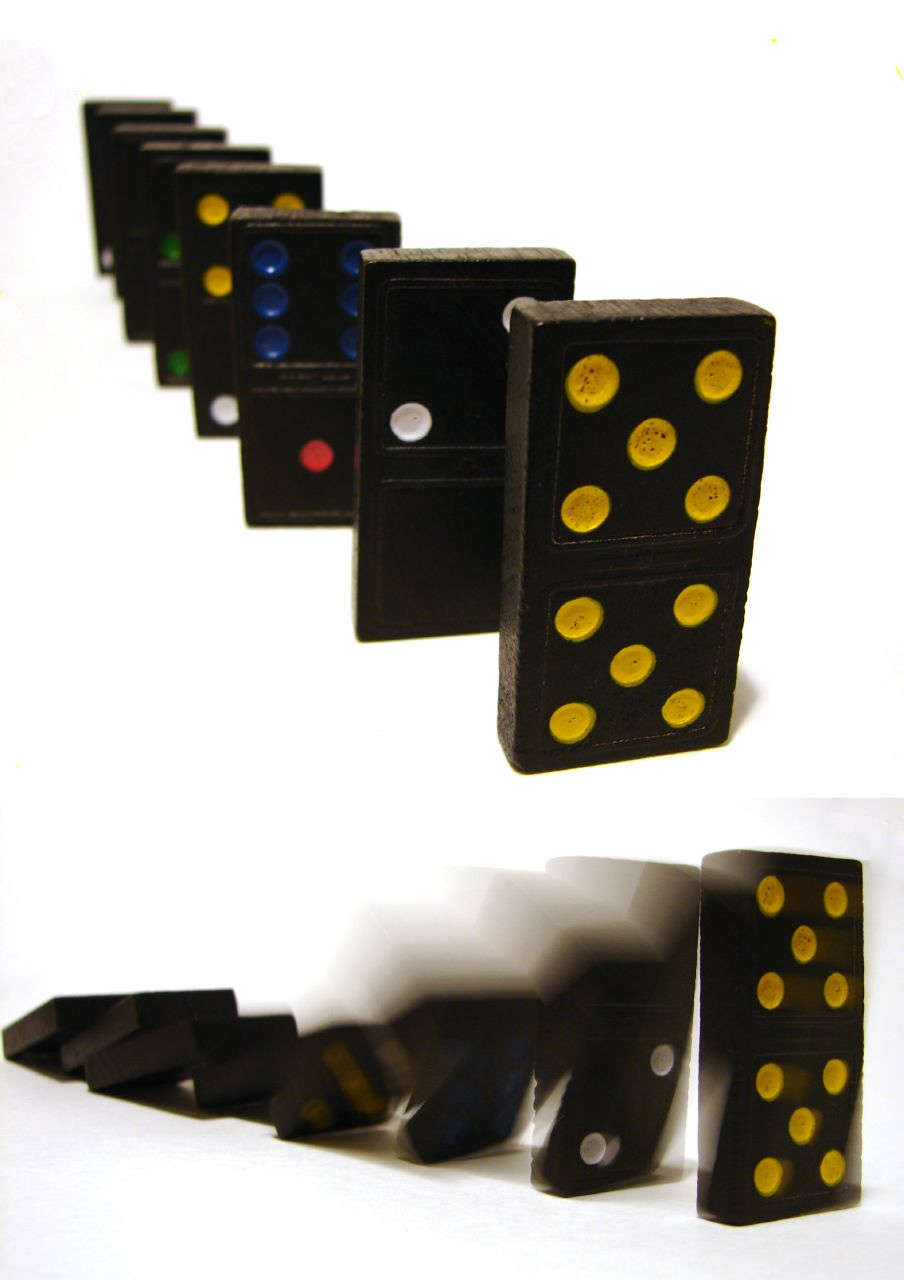 Image of dominos standing in a row and sequentially knocking each other down.